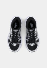Black and silver running shoes with mesh upper, rounded toe, thick white sole, and black laces. Features reflective accents on the sides.