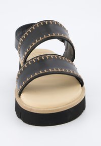 Černé sandály se dvěma širokými popruhy prošívanými světle hnědou nití, béžovou stélkou a silnou černou podrážkou pro zvýšení pohodlí.