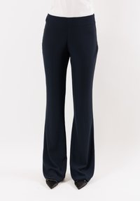 Pantaloni a zampa d'elefante blu navy realizzati in un tessuto liscio e elasticizzato. Presentano una vita alta e delle cerniere alle caviglie per un tocco di dettaglio in più.
