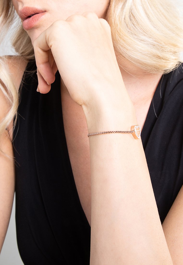 Bracciale in argento con un accento geometrico in oro rosa. Il pezzo presenta una texture liscia e un design minimalista.