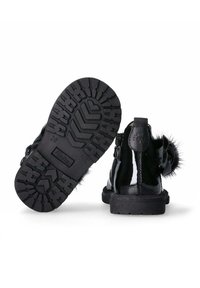 Stivali alla caviglia in pelle verniciata nera con suola in gomma testurizzata. Presentano una cerniera laterale e un accento decorativo in pelliccia ecologica sul retro.
