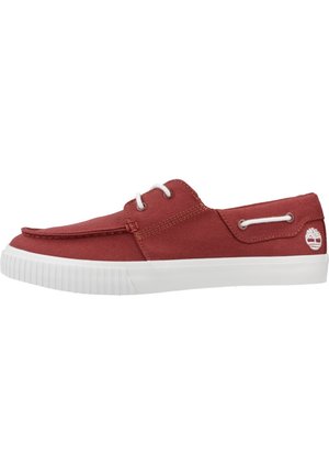Zapatilla de lona roja con suela de goma blanca, diseño de cordones y acento de logo en el lateral. Textura suave y silueta sencilla.