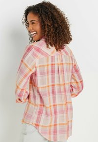 Camicetta a scacchi in tessuto leggero con colori rosa, arancione e bianco. Polsini con bottoni e orlo arrotondato, con dettaglio di piega sul retro.
