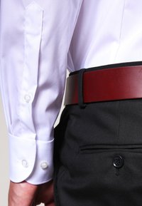 Weißes Langarmhemd mit geknöpften Manschetten, kombiniert mit schwarzen Hosen und einem braunen Ledergürtel. Verfügt über einen glatten Stoff und eine taillierte Passform.