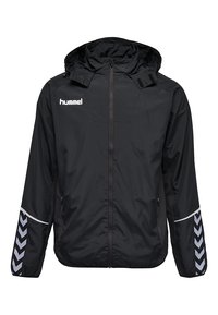 Veste de sport Hummel noire avec capuche, fermeture éclair à l'avant, poches latérales zippées et motif en chevron sur les manches inférieures.