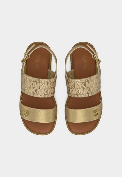 Σανδάλια Michael Kors σε χρυσαφί απόχρωση με δύο λουράκια, το πάνω λουράκι φέρει το λογότυπο MK, μεταλλικό λουράκι μπροστά και πόρπη αστραγάλου.