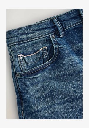 Tmavě modré džínové kalhoty s viditelným švem, přední kapsou a zapínáním na knoflík. Látka vykazuje jemnou strukturu a mírně opotřebovaný vzhled.