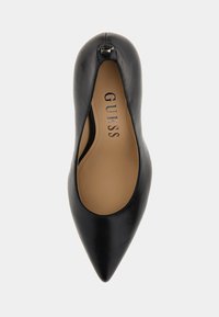 Scarpa nera in pelle con punta affusolata e texture liscia. L'interno presenta il nome del marchio "GUESS" stampato in argento. Dettaglio con zip sul tallone.