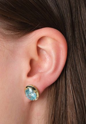 Ohrringe mit goldfarbiger Beschichtung, die einen großen, runden, hellblauen Edelstein zeigen. Die Ohrringe sind mit sichtbaren Krappen sicher befestigt.