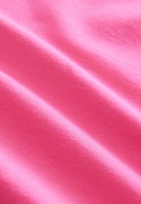 Tela de algodón rosa con una textura suave, que presenta pliegues sutiles y delicados y un ligero brillo, ideal para prendas de vestir.