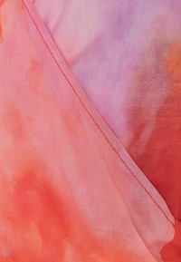 Bufanda de seda con un degradado de tonos rosa y naranja. Presenta una textura suave y un delicado bordado a lo largo del borde.