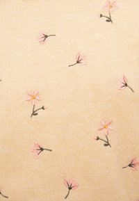 Tissu beige avec de petites fleurs roses brodées et des tiges vertes dispersées sur la surface.