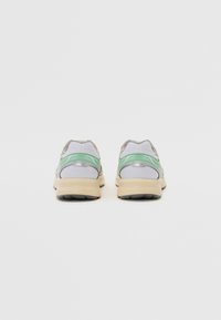 Grå mesh-sneakers med gröna accenter och beige sulor, med en vadderad krage och texturerad sula för bra grepp.