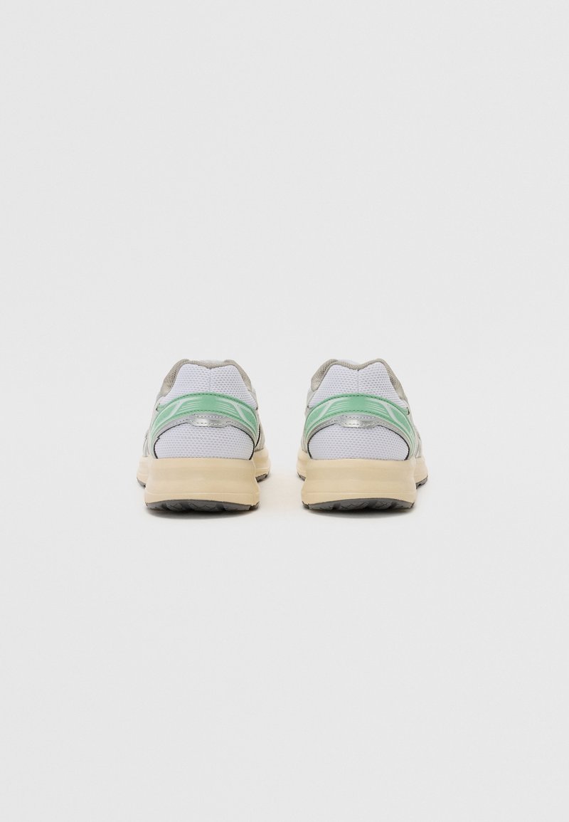 Zapatillas de malla grises con acentos verdes y suelas beige, que cuentan con un collar acolchado y una suela texturizada para mayor agarre.