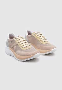 Zapatillas deportivas beige y grises con parte superior de malla, detalles de ante, talón blanco y cordones de color claro. Suelas de goma gruesas para mayor amortiguación.