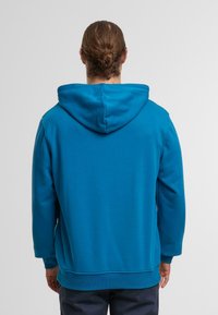 Blue hooded sweatshirt with a kangaroo pocket, ribbed cuffs, and hem. Made of soft fabric, featuring a smooth texture and relaxed fit.