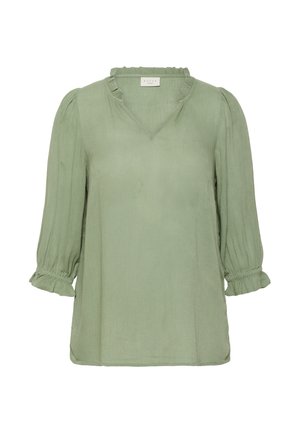 Blouse vert clair avec un col en V et un col à volants. Elle présente des manches trois-quarts avec des poignets froncés et un tissu texturé.