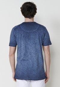 Lyhythihainen t-paita liukuvärjätyssä tummansinisessä sävyssä, pehmeästä kankaasta, jossa on hieno tekstuuri. Pyöreä kaula-aukko ja suora helma takana.