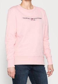 Růžová mikina z bavlněné směsi s kulatým výstřihem, žebrovanými manžetami a lemem, s logem "TOMMY HILFIGER" na přední straně.