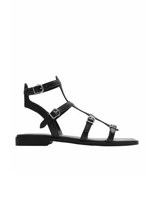 Sort flad læder gladiatorsandal med flere justerbare spænderemme og en lav, firkantet hæl.