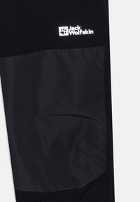 Svarte bukser med en kontrasterende matt tekstur og et blankt logo-patch. Glatt materiale med sydd detaljer for holdbarhet.