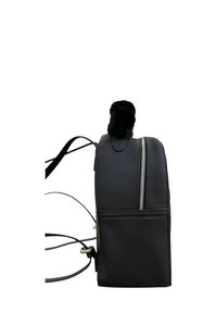 Zaino in pelle nera con una cerniera verticale, forma arrotondata, tasca frontale e un morbido pom-pon nero come decorazione nella parte superiore.