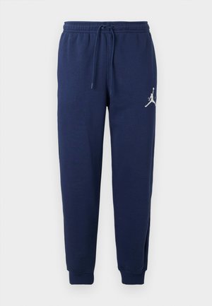 Pantalons de survêtement bleu marine en matériau doux, dotés d'une taille avec cordon de serrage et de poignets côtelés ; un logo blanc est imprimé sur la jambe gauche supérieure.