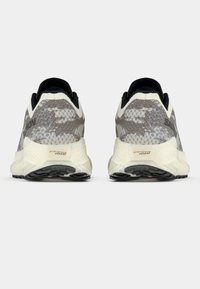 Ελαφριά παπούτσια για τρέξιμο με γκρι ανάγλυφο πάνω μέρος και μαύρη λεπτομέρεια, ανθεκτική λευκή ενδιάμεση σόλα και μαύρη εξωτερική σόλα με λαβές.