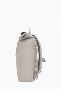 Sac à dos gris à rabat avec un extérieur lisse, des bretelles rembourrées et une fermeture éclair sur le côté. Design épuré et minimaliste.