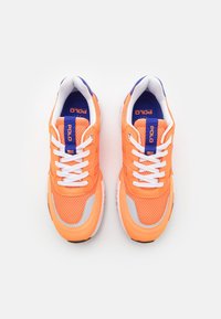 Orange mesh sneakers med vita snören, grå detaljer och en blå vadderad krage. Har en logotags på tungan för varumärkesidentifiering.