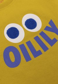 Geel katoenen t-shirt met een blauwe, textuurachtige letter "O" en twee grote witte en blauwe oogontwerpen. Casual, eenvoudig ontwerp met gedurfde graphics.