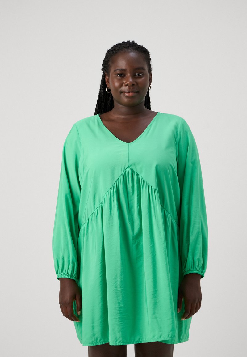 Πράσινο, μακρύ μανίκι φόρεμα με V-λαιμό και συγκεντρωμένη μέση. Φτιαγμένο από ελαφρύ ύφασμα, διαθέτει άνετη εφαρμογή και απαλή υφή.