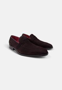 Donkerbruine suede loafers met een strak ontwerp, spitse neus en subtiele stiksels. Het interieur heeft een contrasterende rode voering.