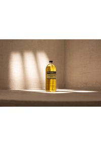 Bottiglia di plastica ambra con tappo nero, con un'etichetta che presenta testo e grafica. Ambientata su uno sfondo testurizzato di un marrone chiaro.