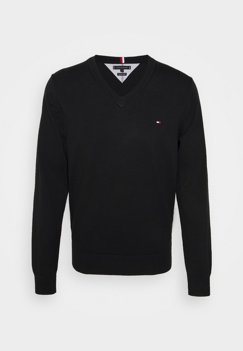 Pull noir à manches longues avec col en V, petit logo rouge, blanc et bleu sur la poitrine gauche, et poignets et ourlet côtelés.