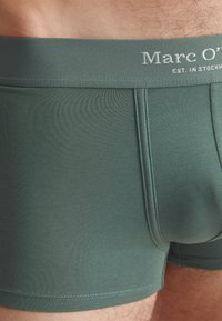 Dunkelgrüne Boxershorts mit weicher Textur, elastischem Bund mit "Marc O'"-Branding und Flachnähten für zusätzlichen Komfort.