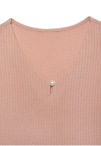 Helles rosa, strukturiertes Oberteil mit V-Ausschnitt und einer Perlenknopfdetail in der Mitte. Weicher Stoff mit einem dezenten, gewebten Muster.