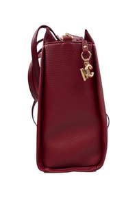 Borsa a mano rossa in pelle con superficie testurizzata, un accento in metallo dorato e un charm che mostra "KC". Presenta due manici per la spalla.