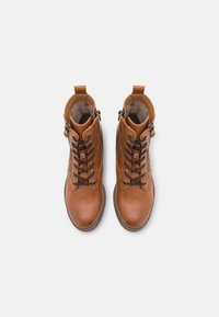 Paire de bottines marron en cuir à lacets avec fermetures éclair sur le côté et languettes à l'arrière, vues de dessus sur un fond blanc.
