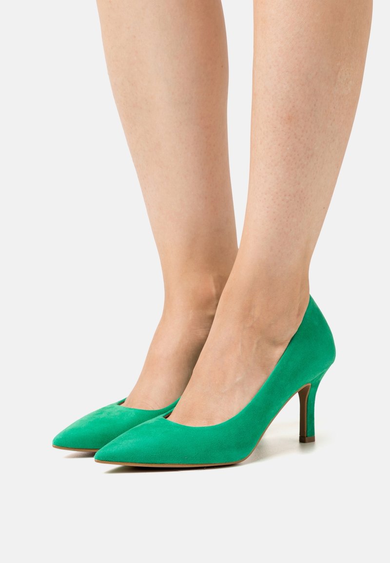 Chaussures à talons hauts en daim vert avec un design à bout pointu et un talon élancé. Texture lisse avec une finition mate, sans motifs ni accents visibles.