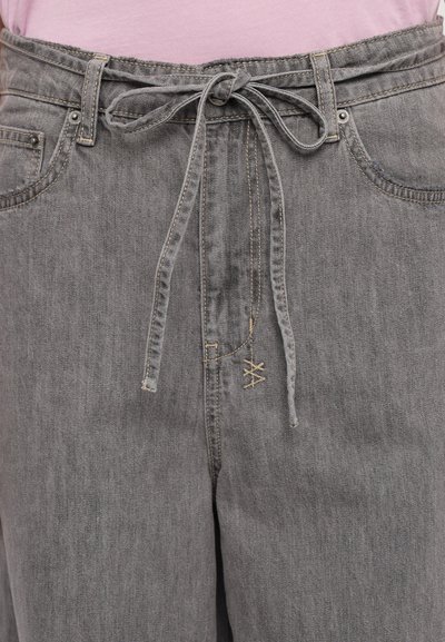 Gray denim pants with a tied front detail, five-pocket design, and beige stitching accents. Material appears soft with a slightly worn texture.