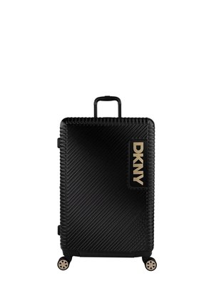 Maleta rígida negra con ranuras diagonales, logo dorado de DKNY, asa retráctil, cuatro ruedas y superficie texturizada para un mejor agarre.