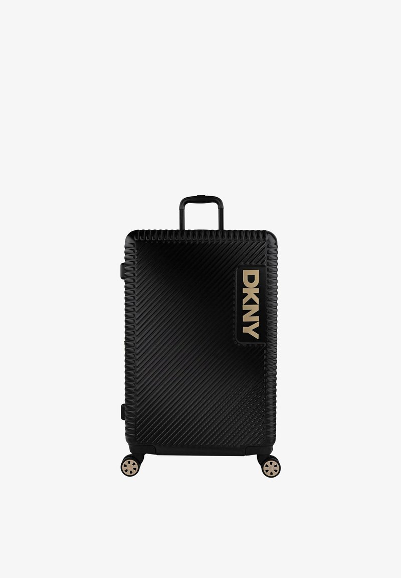 Maleta rígida negra con ranuras diagonales, logo dorado de DKNY, asa retráctil, cuatro ruedas y superficie texturizada para un mejor agarre.