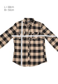 Chemise à carreaux beige et noire à manches longues posée à plat avec des rubans à mesurer indiquant une longueur de 68 cm et une largeur de 50 cm.