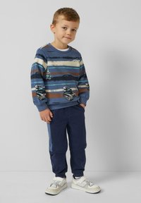 Blau gestreifter Sweatshirt mit Mustern und marineblauen Hosen, kombiniert mit weißen Turnschuhen. Verfügt über gerippte Bündchen und ein lässiges Fit-Design.