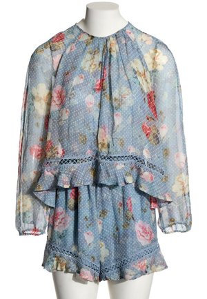 Blouse bleue transparente à motif floral avec manches longues et short assorti, les deux avec des volants et une bordure en dentelle sur un mannequin blanc.