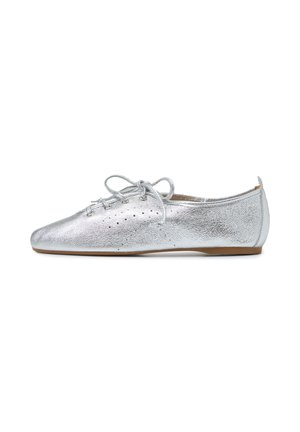 Scarpa piatta in pelle metallizzata argento con lacci, piccole perforazioni e suola marrone a basso profilo, vista dal lato esterno.