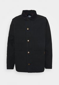 Giacca nera in canvas con colletto in corduroy, due tasche frontali e bottoni in ottone. Linee pulite e design a taglio dritto.