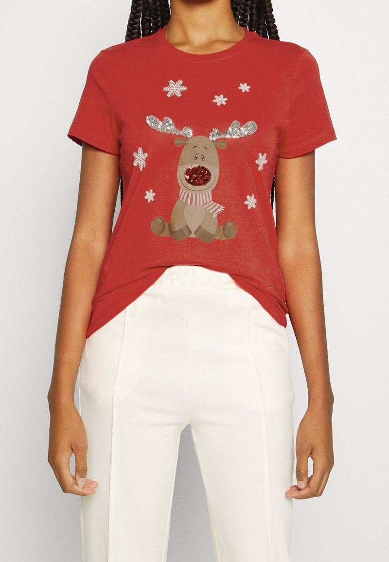 Camiseta de algodón roja con un gráfico de un reno con cuernos brillantes y una nariz roja, rodeado de formas de copos de nieve blancos.