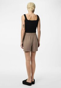 Top noir à côtes avec encolure carrée, associé à un short beige clair avec une taille élastique et des chaussures à plateforme noires à enfiler.